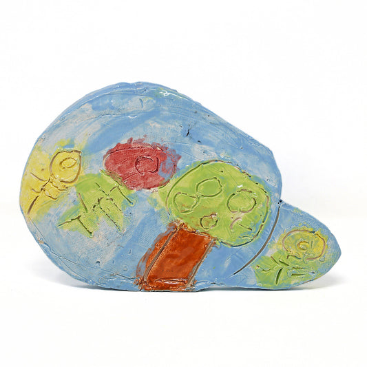 Ceramic landscape with a tree and three flowers against a blue sky. 