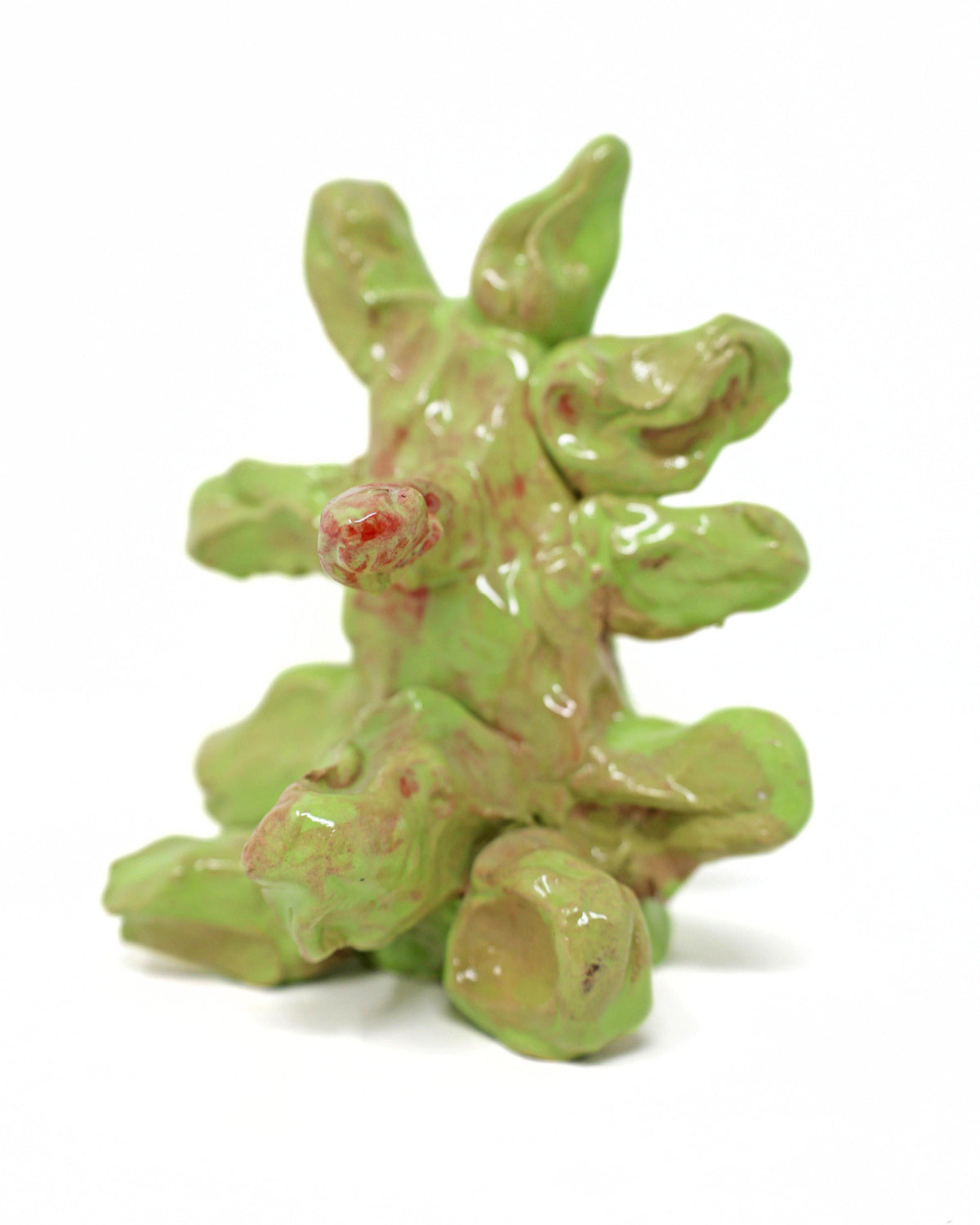 This abstract sculpture is heavily coated in a lime green glaze. The thick application of glaze creating a drooping effect. The piece has 7 appendages that protrude from the center.