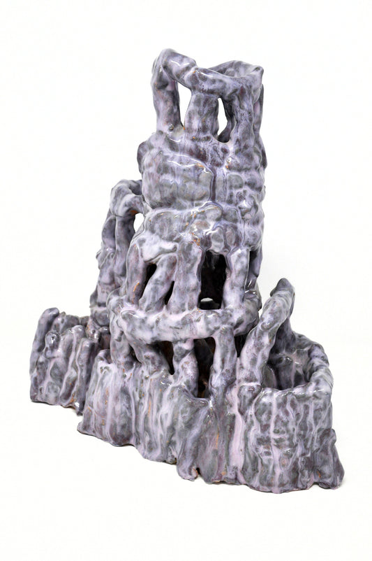 A ceramic sculpture of a tower. Glossy lilac glaze is layered over a darker purple glaze to create a mottled texture. The tower is three tiers and wider at the base. It's made of little cylinders: some are stacked vertically and others are wrapped around the tower in horizontal bands. There are gaps between each cylinder through which the white background is visible.