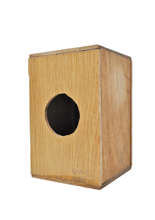 The backside of a wooden cajon, a Peruvian hand drum, with a natural brown finish, photographed against a white background.