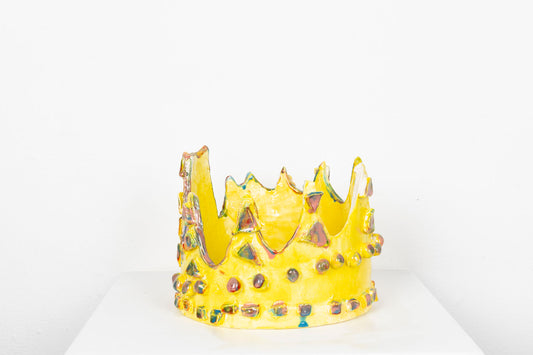 Glazed ceramic sculpture of a bright yellow jeweled crown with iridescent gems.