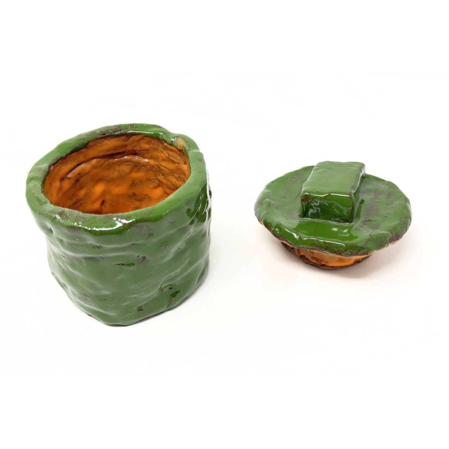 The same ceramic vessel, photographed with the lid off and sitting beside the base. In this image we can see that the interior of the coil vessel is glazed bright orange. 