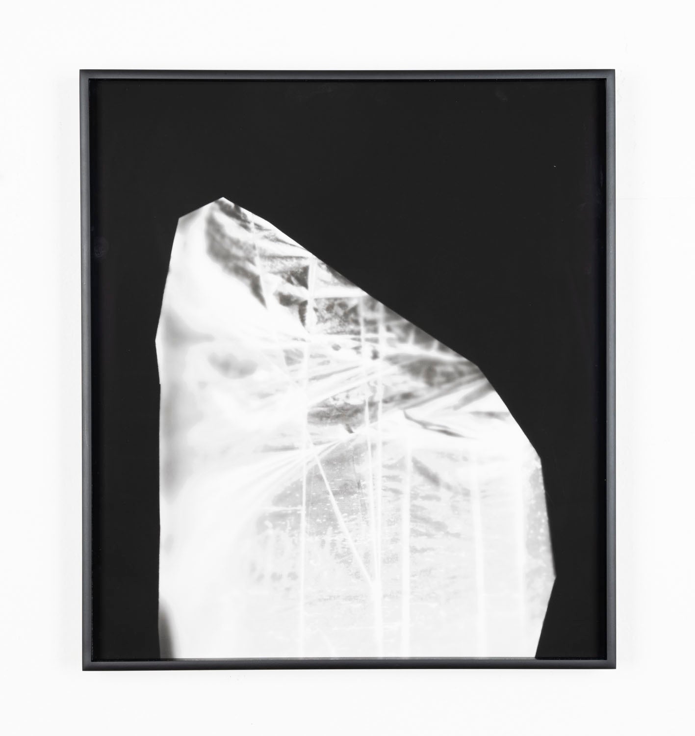 An abstract silver pigment print on black paper in a black frame. The image is contained in an oblong, half-oval shape and features intersecting horizontal and vertical beams of light. 
