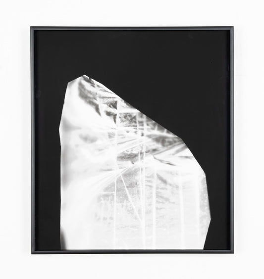 An abstract silver pigment print on black paper in a black frame. The image is contained in an oblong, half-oval shape and features intersecting horizontal and vertical beams of light. 