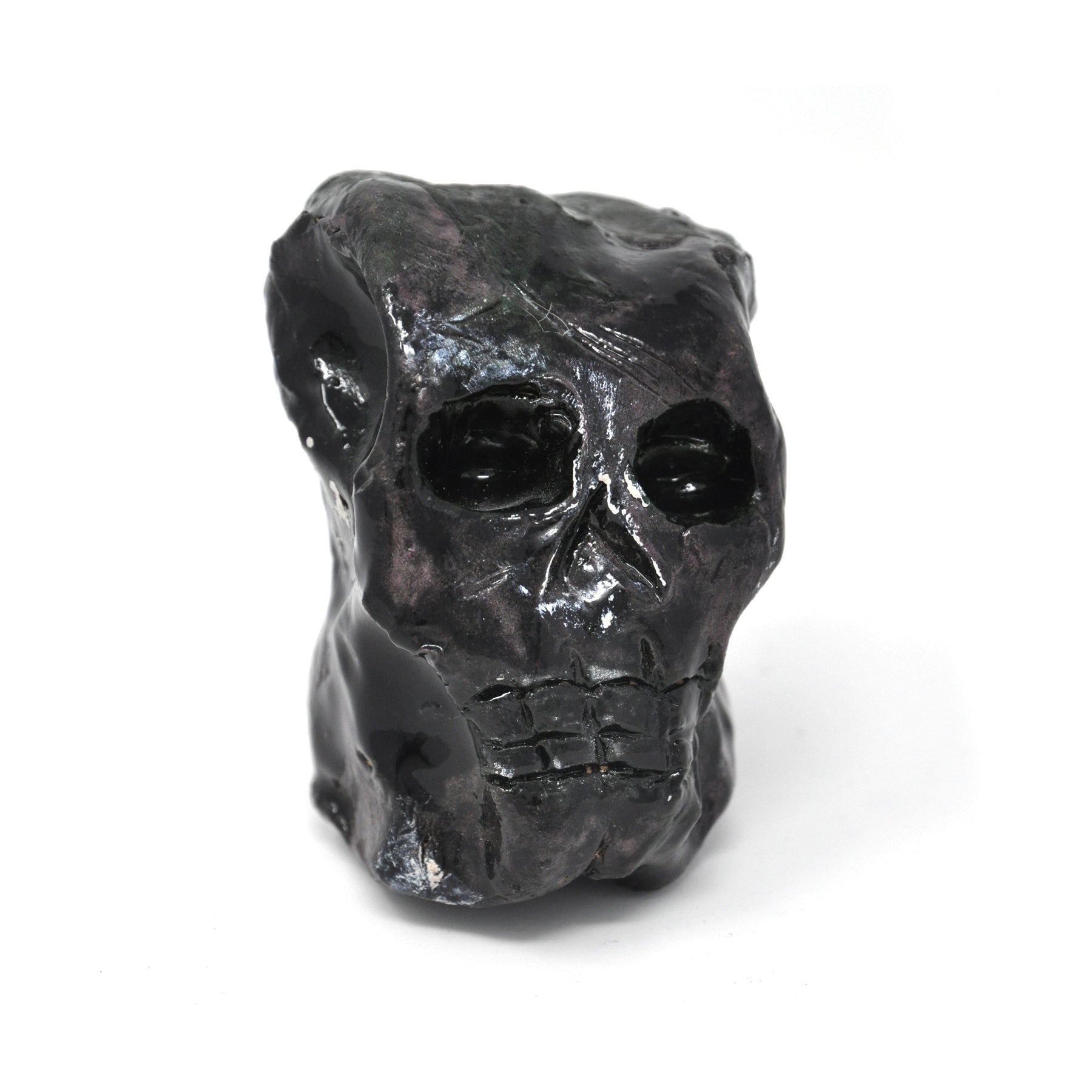 a ceramic sculpture of a smiling skull, painted all black.