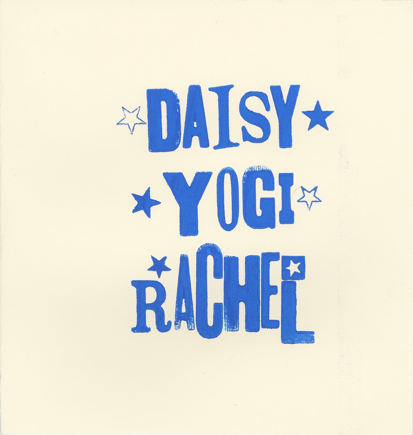 a letter press print on a tan square of paper. In blue ink, the artist has printed the names of their 2 dogs and their own name in a stack. It reads, from top to bottom: Daisy, Yogi, Rachel. There are 5-pointed stars flanking each name.  