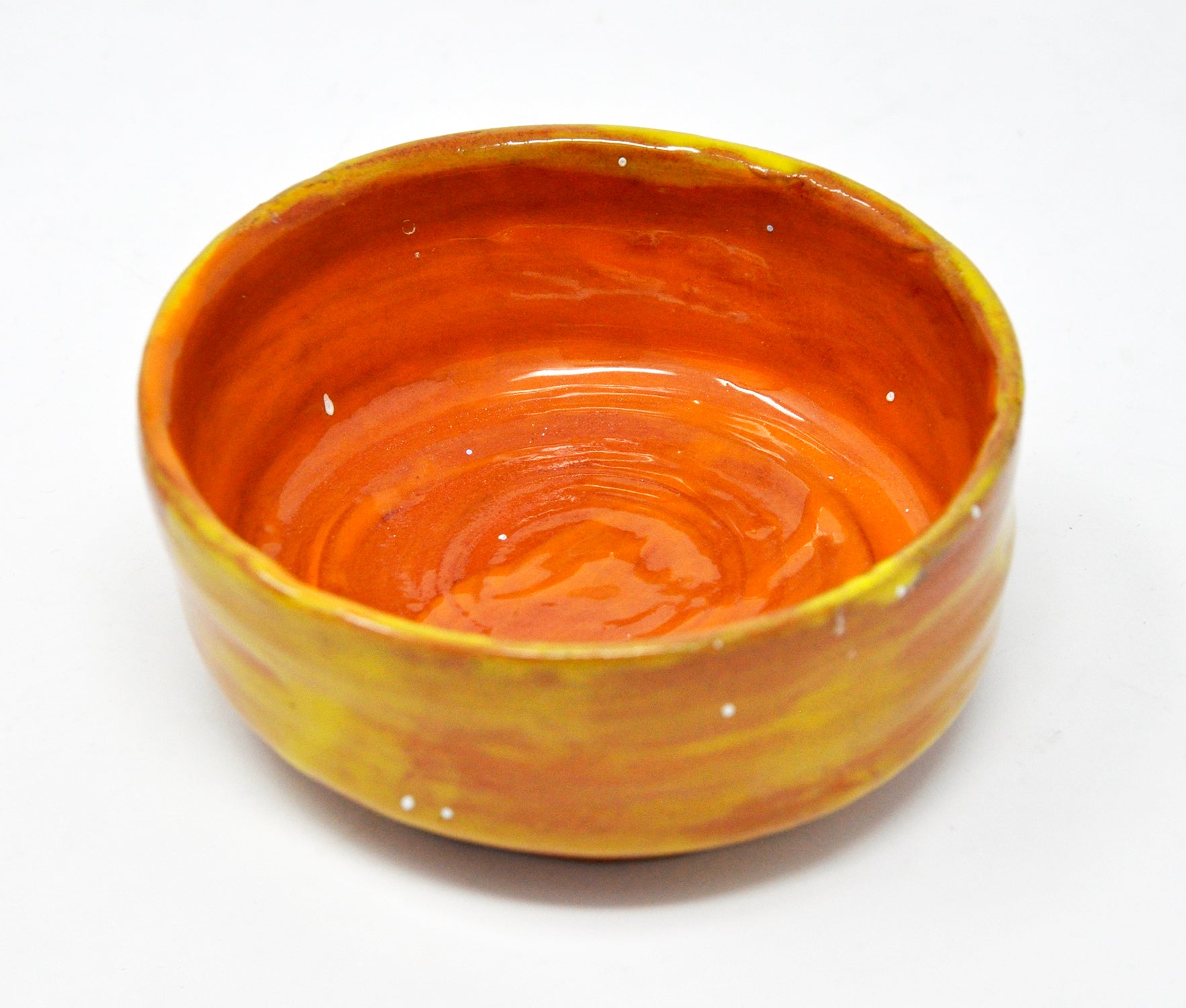 a small wheel-thrown ceramic bowl, glazed all over in bright glossy orange