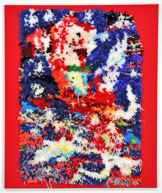 A tufted rug attached to the center of a bright red piece of fabric. The fabric has been stretched over stretcher bars so that the piece can hang like a painting on the wall. The tufted rug is a tall rectangle made of short pieces of yarn. The surface features an abstract branching swirl of blue, white, and red, with small flecks of every color of the rainbow peppered around the surface. 