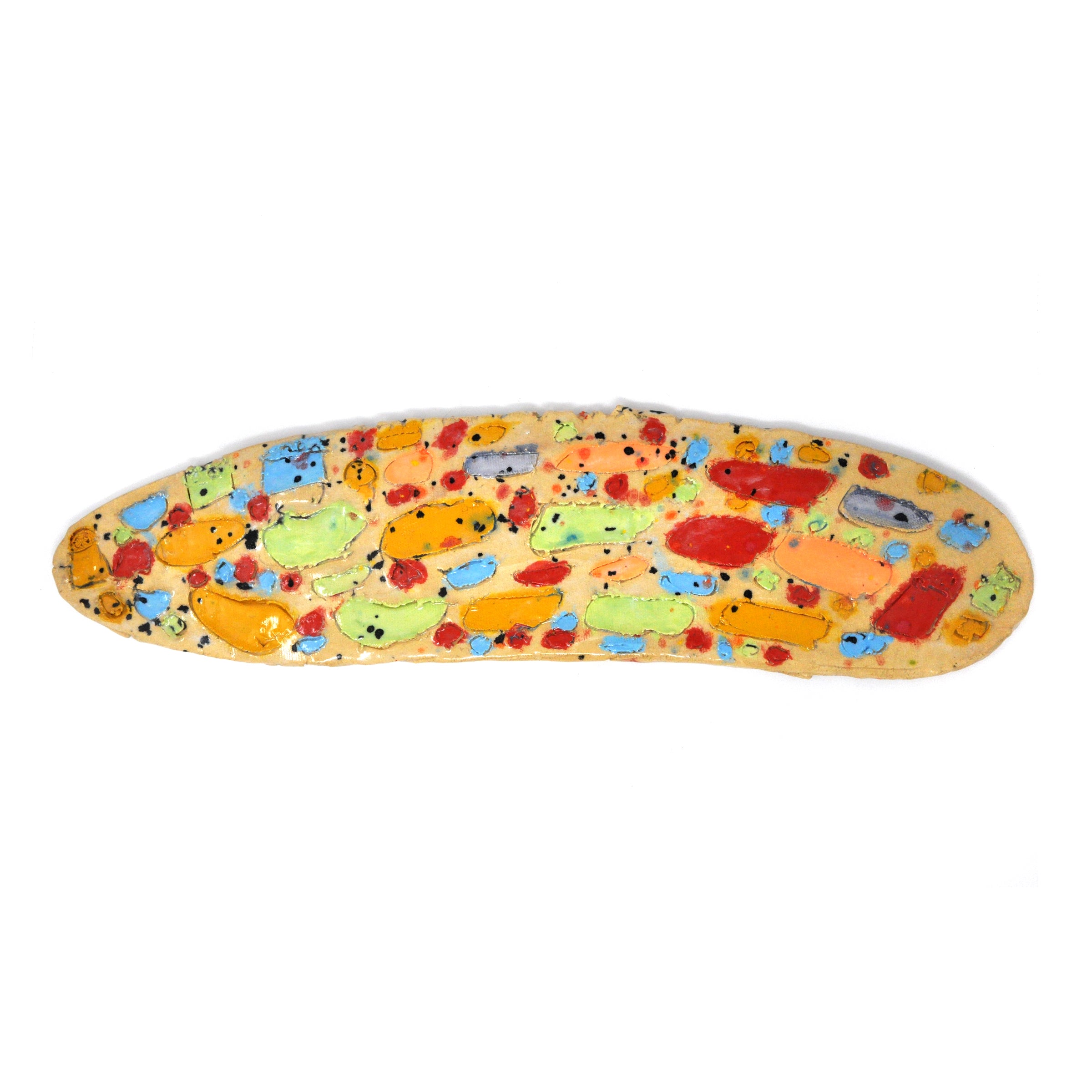 An oblong ceramic slab photographed from above on a white surface. The slab is glazed orange and sprinkled with festive confetti dots in black and red and blue. Multiple egg-like shapes fill the surface and are painted red, green, orange, and blue.