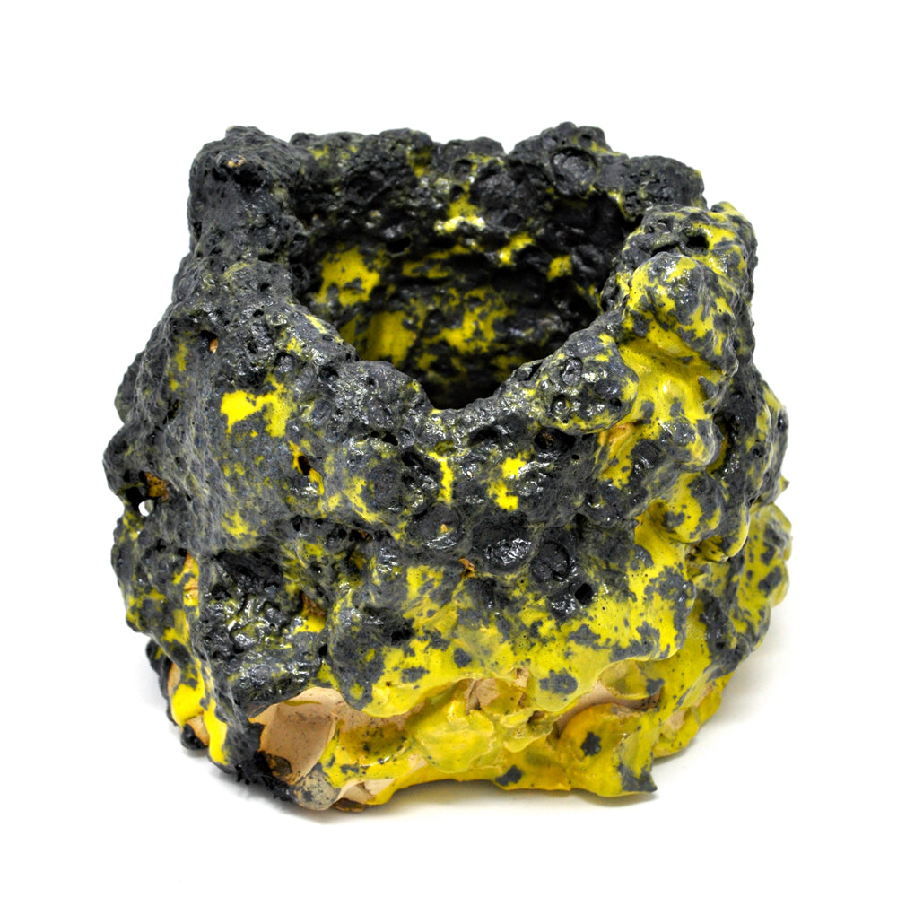 The same sculpture, photographed from a different angle. The opening of the pot is more visible, showing how the mixture of yellow and black color, as well as rough and smooth textures, continues on into the interior of the vase. 