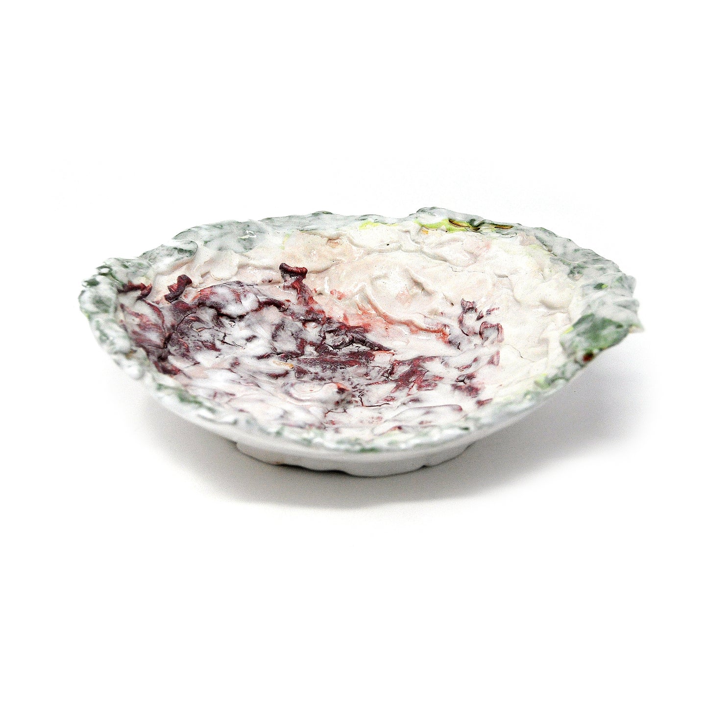 a glazed ceramic sculpture in the shape of a shallow bowl, photographed on a white backdrop. The bowl was made using the coil pot technique. The sculpture has been painted with swathes of green, white, and maroon glaze.