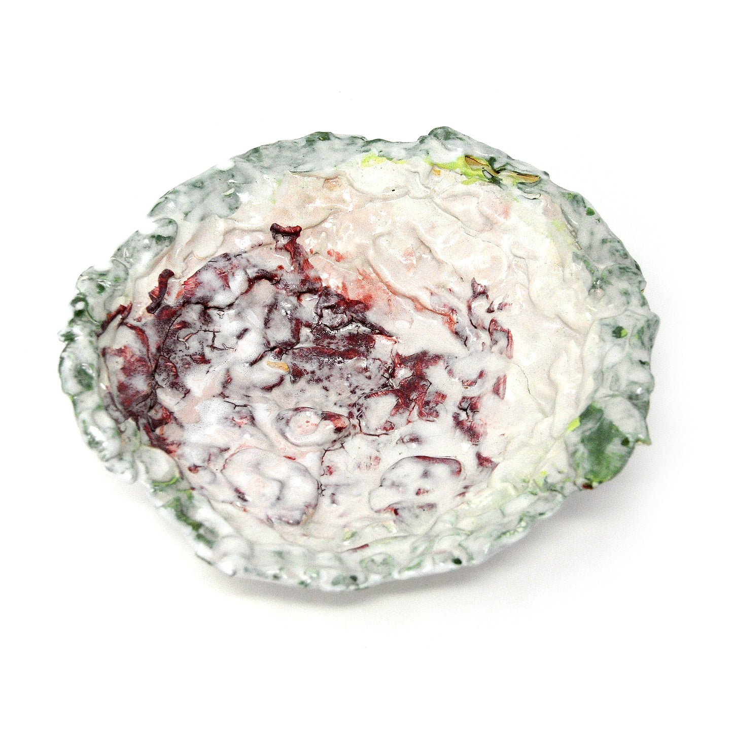 An image of the same shallow bowl, photographed from above on a white surface. Here the interior of the bowl is in focus, showing the meandering areas of maroon melting into larger spaces of white glaze. The rim of the bowl is a mottled green color. 