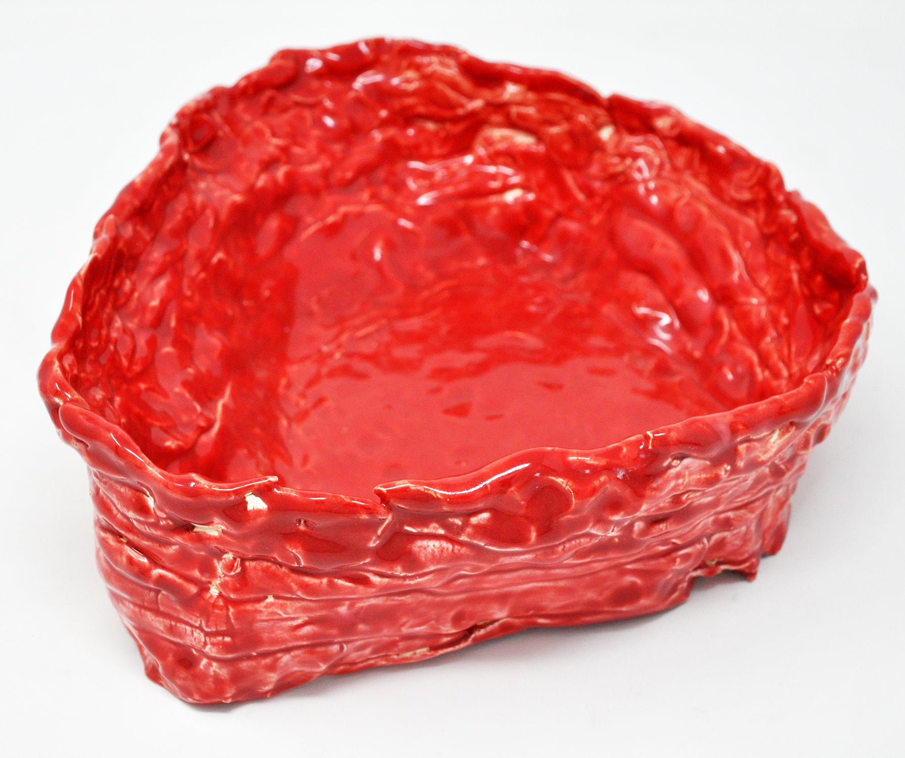 The same sculpture photographed from above. Here the interior of the vessel is in focus. The entire work is glazed in a shiny red color and each stacked coil that wraps around the perimeter of the piece is discernible.