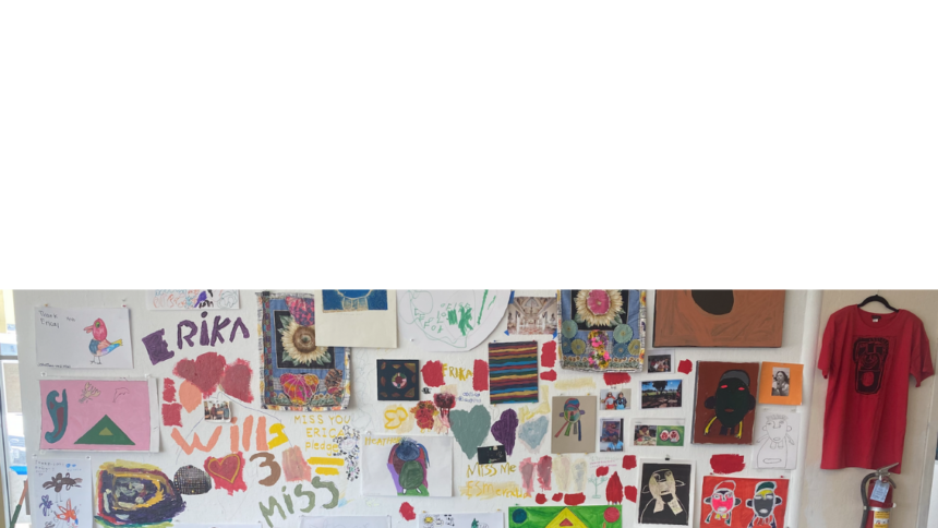 A wall in the NIAD gallery with many artworks hung on the wall and messages painted and drawn directly on the wall in tribute to NIAD artist Erika Martinez.