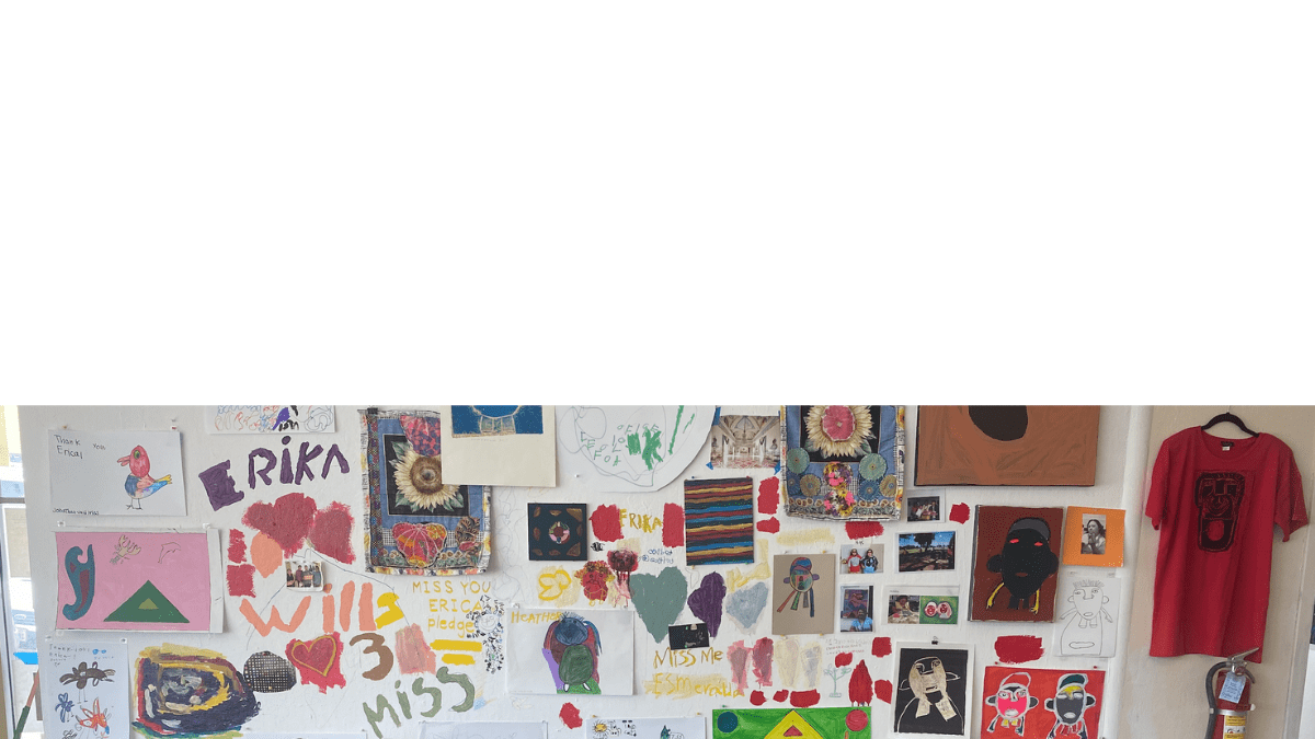 A wall in the NIAD gallery with many artworks hung on the wall and messages painted and drawn directly on the wall in tribute to NIAD artist Erika Martinez.