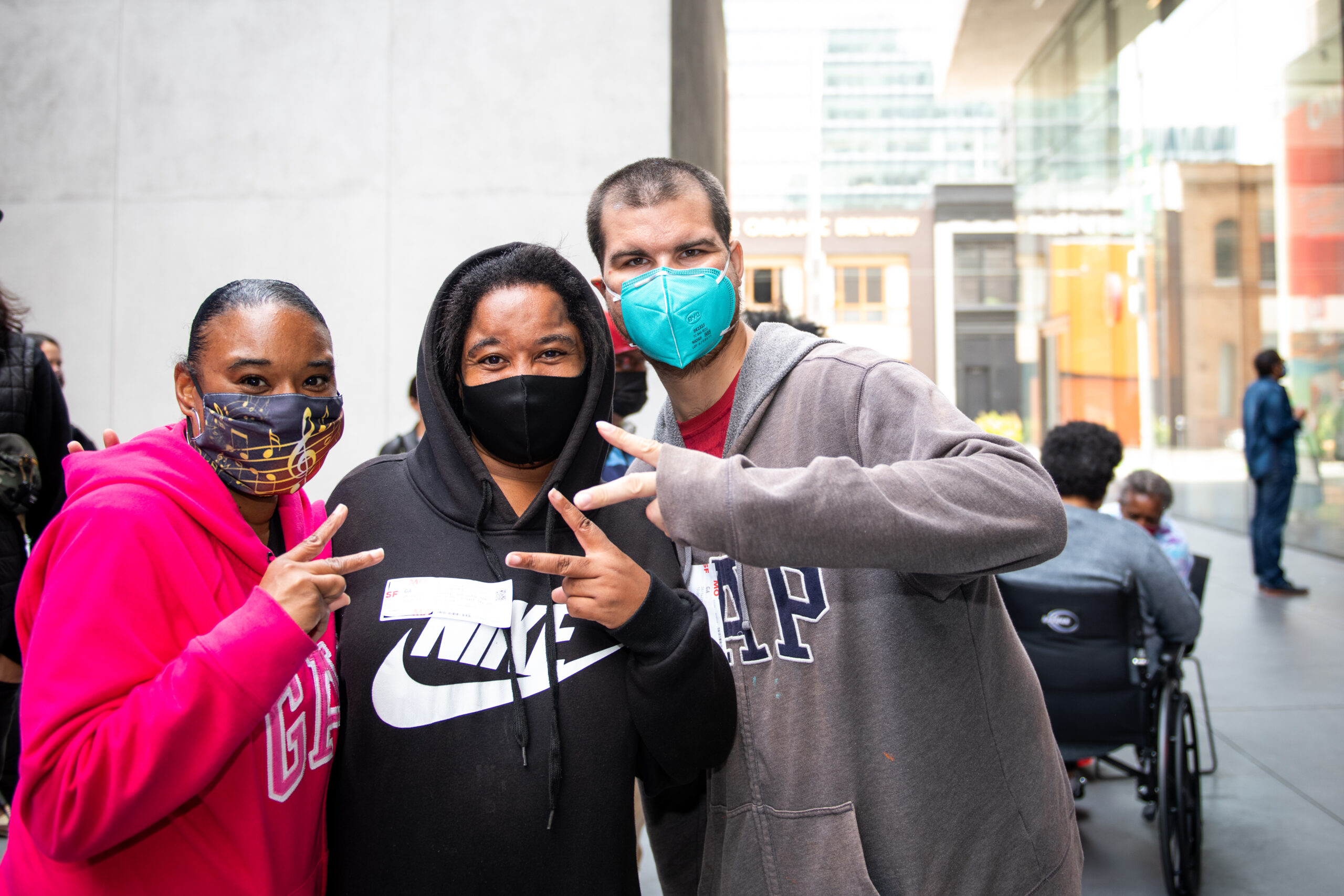 Three NIAD artists giving peace signs at the SFMOMA mini mural festival