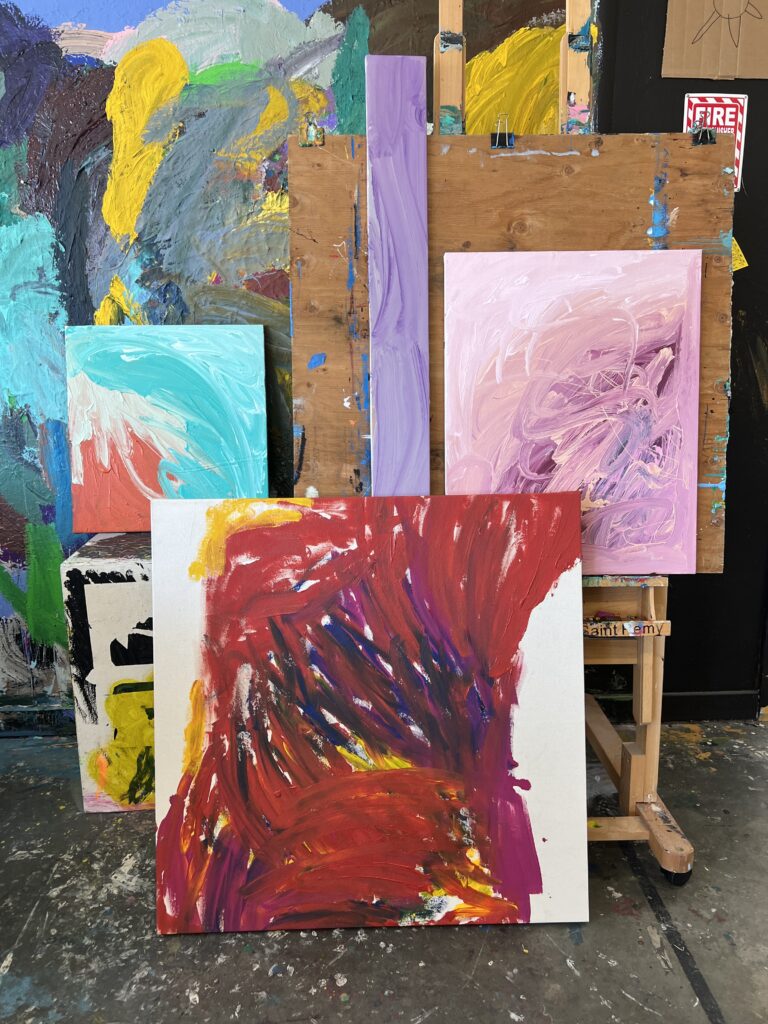 Four abstract canvases displayed on easels and leaning against the wall in NIAD's studio.